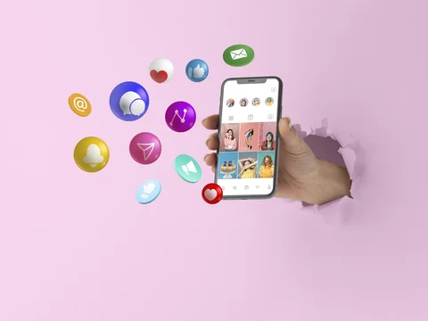 A hand holding a smartphone displaying a social media interface, surrounded by colorful social media icons, symbolizing social media marketing trends.